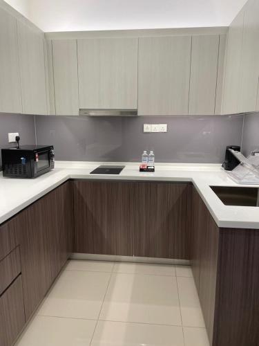 a kitchen with white counter tops and wooden cabinets at Suasana Suites Johor Bahru City Centre in Johor Bahru