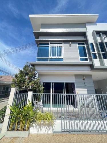 a white house with a white fence in front of it at Townhome Sattahip in Sattahip