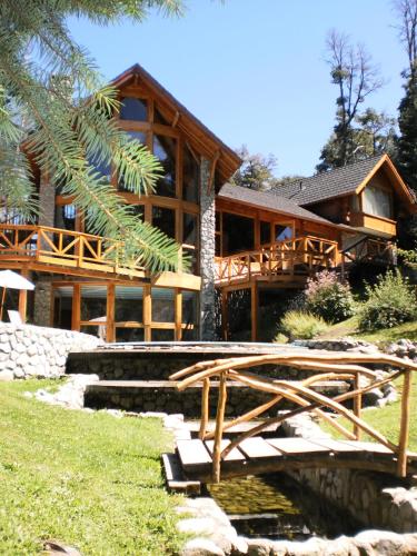 a log house with a bridge in front of it at Aldea Bonita in Villa La Angostura