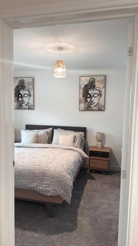 a bedroom with a bed and two pictures on the wall at 3 Bedroom Brand New Whiteley Home with Hot Tub in Botley