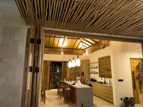 a kitchen with a bar and a person in the background at Villa Elior Selong Belanak, South Lombok in Selong Belanak