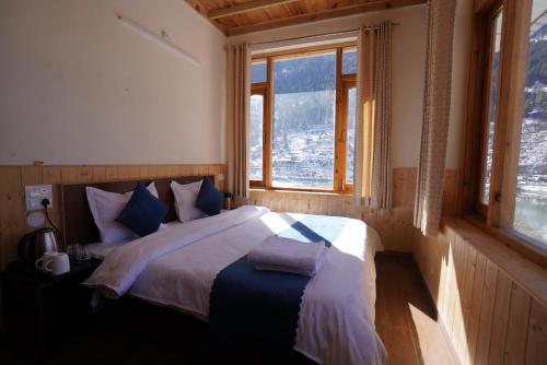 a bedroom with a bed in a room with windows at The Kamru Riverside Camps and Resorts in Sāngla