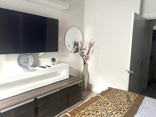 a living room with a television and a vase with flowers in it at LIGUANEA -ONE BEDROOM OASIS near US EMBASSY in Barbican