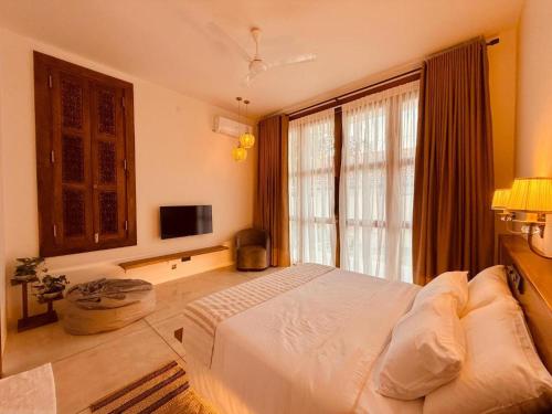 a bedroom with a white bed and a television at Madiha Venus in Matara