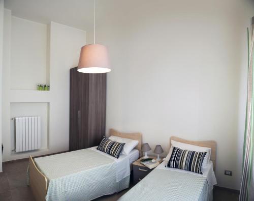 2 Betten in einem kleinen Zimmer mit einer Lampe in der Unterkunft Apartment Corso Cavour in Bari