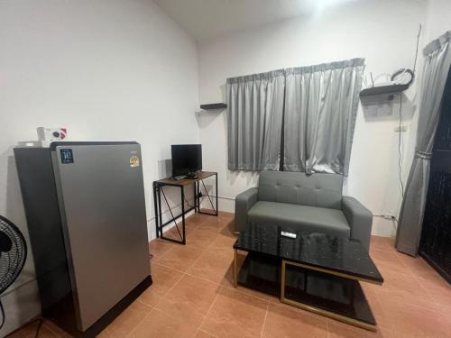 Una sala de estar con una silla y un televisor. en Nine Blue 4 BD Villa, en Pattaya South