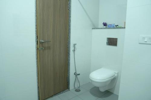 Un baño con inodoro y puerta de madera. en Mannat Resort, en Bikaner
