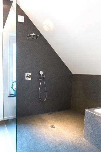 a bathroom with a shower on a black wall at Le Coin Cocoon in Aywaille