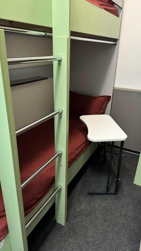 a room with bunk beds with a table and a stool at Лучший хостел Алматы - Масанчи in Almaty