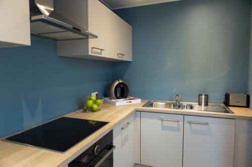 a kitchen with white cabinets and a sink at Le Coin Cocoon in Aywaille