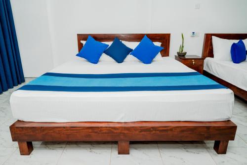 a bedroom with a bed with blue and white pillows at Villa Baranzio in Tangalle