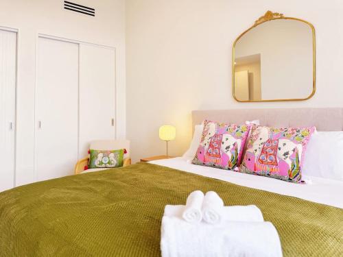 a bedroom with a bed with a mirror and towels at A Home Away From Home - Luxury 4Beds ASB Showgrounds & Cornwall Park in Auckland