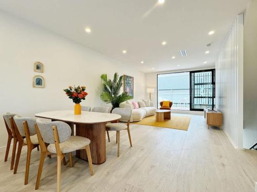 uma sala de estar com uma mesa, cadeiras e um sofá em A Home Away From Home - Luxury 4Beds ASB Showgrounds & Cornwall Park em Auckland
