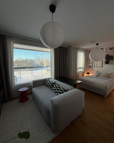 a living room with a couch and a large window at Cozy Top-Floor Studio in Turku - Near City Center in Turku