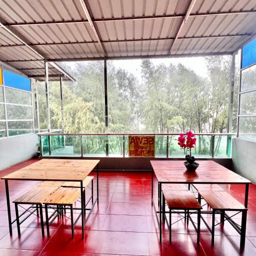 two tables and chairs in a room with a large window at DI TAMBAK 2 Homestay in Pontian Kecil