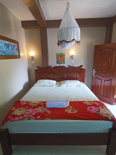 a bedroom with a large bed with a red blanket at Fidodido Guesthouse Jungle trekking in Bukit Lawang