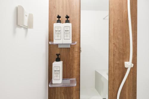 a bathroom with three bottles of soap on a shelf at Shinjuku Raise OG House in Tokyo
