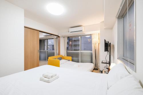 a bedroom with a white bed and a yellow chair at Shinjuku Raise OG House in Tokyo