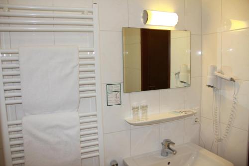 a white bathroom with a sink and a mirror at Alpenhotel Brennerbascht in Bischofswiesen