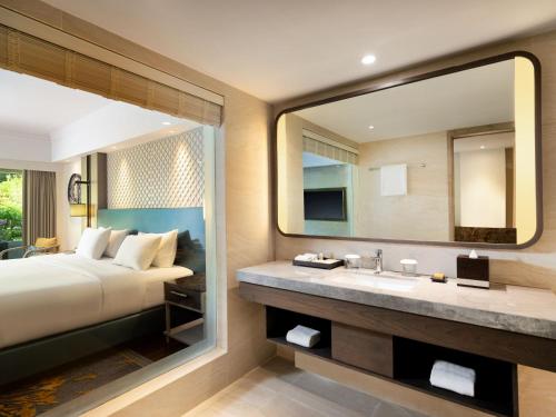 a bedroom with a bed and a sink and a mirror at Hilton Bali Resort in Nusa Dua