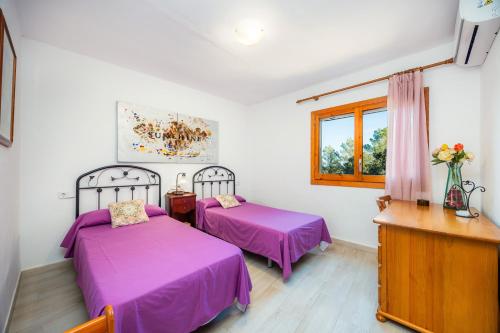 two beds in a room with purple sheets at S' Alzina in Sencelles