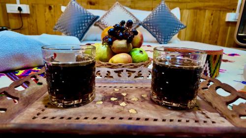 two glasses of soda on a table with a basket of fruit at The Luxe Cascades JIbhi in Jibhi