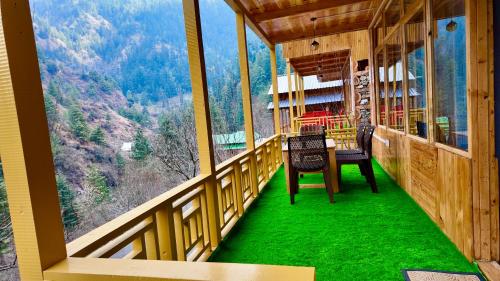 a room with a table and chairs on a balcony at The Luxe Cascades JIbhi in Jibhi