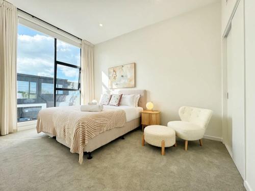 a white bedroom with a bed and a chair at Luxury 4Bedroom Townhouse in Central Greenlane - ASB Showgrounds & Cornwall Park in Auckland