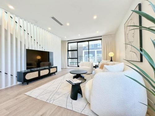 a living room with a white couch and a tv at Luxury 4Bedroom Townhouse in Central Greenlane - ASB Showgrounds & Cornwall Park in Auckland
