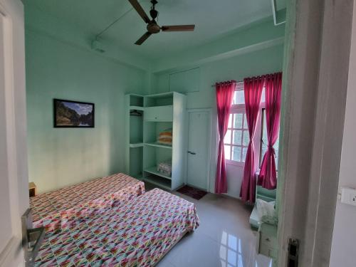 a bedroom with two beds and pink curtains at Greenview City Stay Apartments in Āīzawl