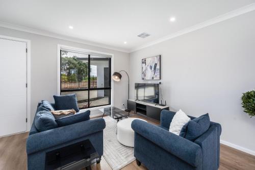 a living room with two blue chairs and a tv at Whispering Vines in McLaren Vale