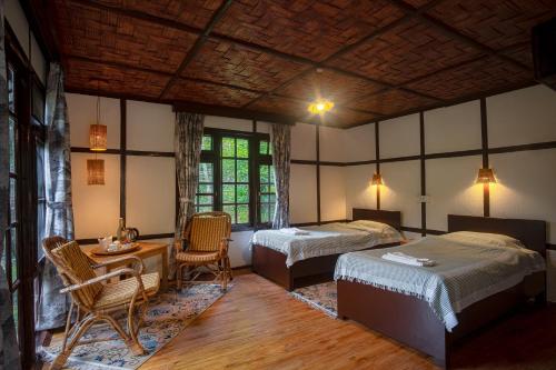 a bedroom with two beds and a table and chairs at Martam Village Resort in Gangtok