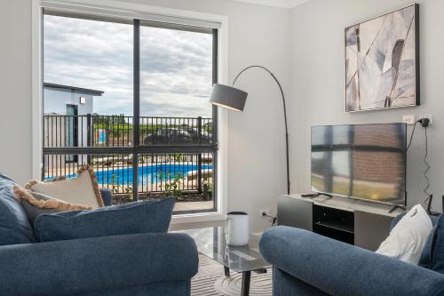 a living room with two blue chairs and a television at Whispering Vines in McLaren Vale