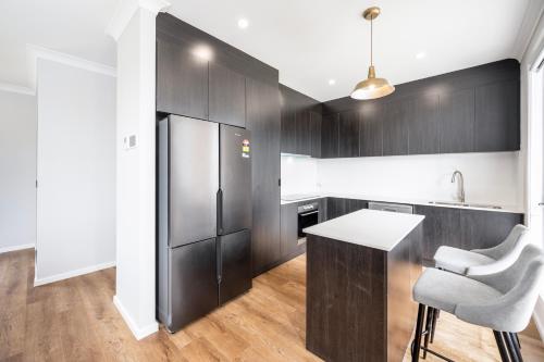 a kitchen with black cabinets and a refrigerator at Whispering Vines in McLaren Vale