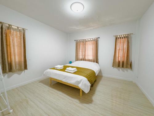 a white bedroom with a bed and two windows at ดารัดวัลเลย์ Darad Valley in Sara Buri
