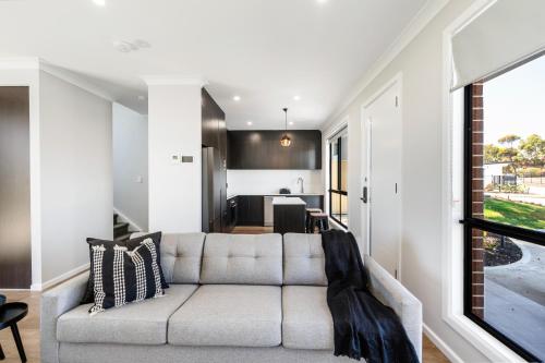 a living room with a couch and a kitchen at Whispering Vines in McLaren Vale