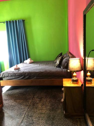 a bedroom with a bed with a green wall at Bat Chum Villa in Phnom Penh
