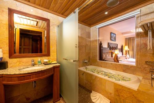 a bathroom with a tub and a sink and a mirror at Bayon Era Hotel in Siem Reap