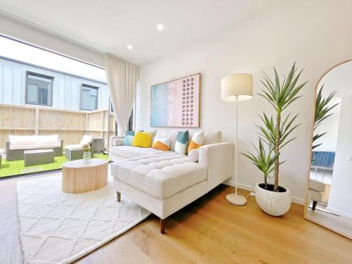 a living room with a white couch and a table at Tranquil Townhouse 2BR & 1 Study with Free Parking & Backyard in Auckland