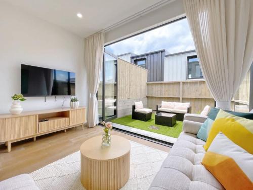 a living room with a couch and a large window at Tranquil Townhouse 2BR & 1 Study with Free Parking & Backyard in Auckland