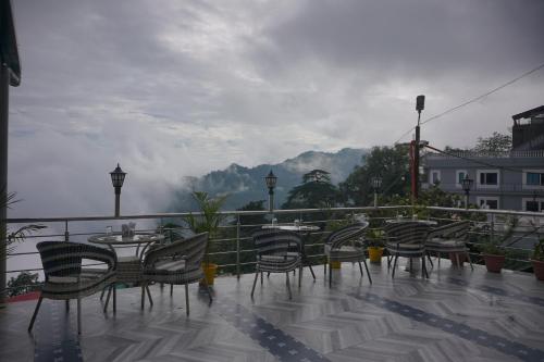 a group of chairs and tables on a balcony with a view at Sangam by Stotrak, Jhula Ghar Mussoorie in Mussoorie