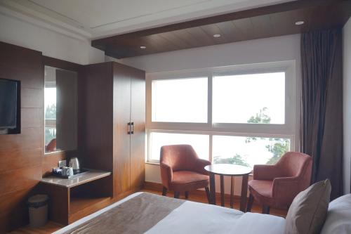 a hotel room with a bed and a table and chairs at Sangam by Stotrak, Jhula Ghar Mussoorie in Mussoorie