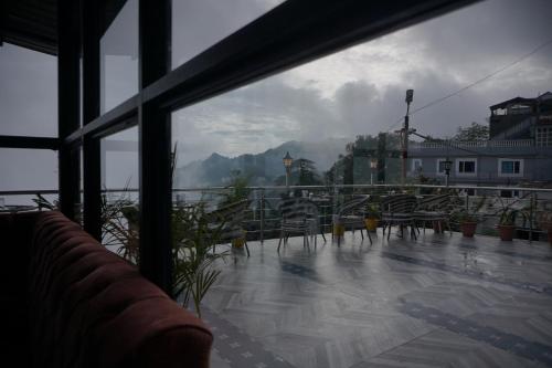 a balcony with chairs and a view of a mountain at Sangam by Stotrak, Jhula Ghar Mussoorie in Mussoorie