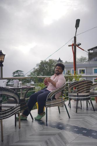 a woman sitting in a chair on a patio at Sangam by Stotrak, Jhula Ghar Mussoorie in Mussoorie