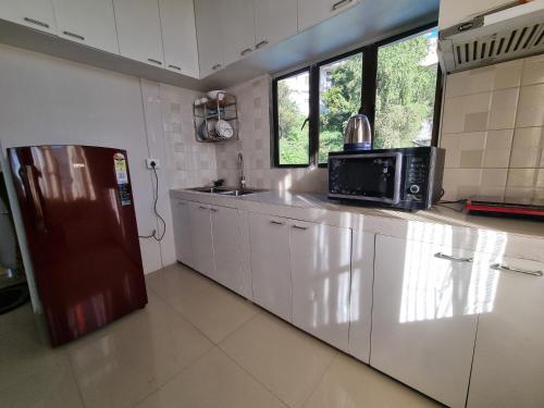 a kitchen with a microwave and a refrigerator in it at Greenview City Stay Apartments in Āīzawl