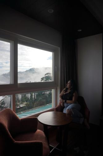 a woman sitting in a room looking out a window at Sangam by Stotrak, Jhula Ghar Mussoorie in Mussoorie