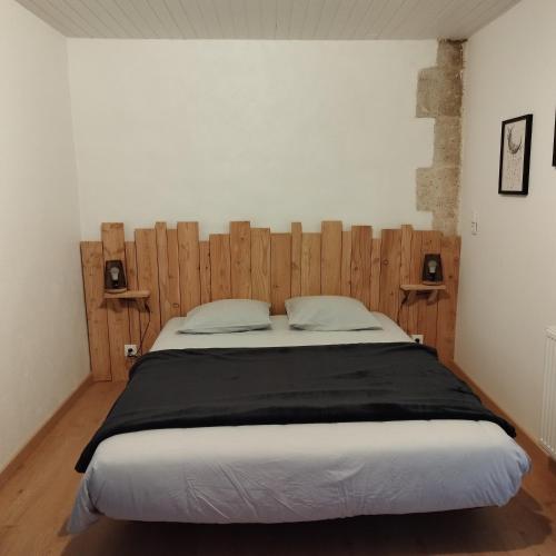 une chambre avec un grand lit avec une tête de lit en bois dans l'établissement Camping des Tourbières - Gîtes, à Vendoire