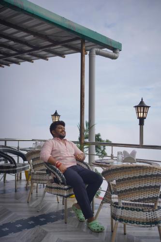 a man sitting in a chair on a patio at Sangam by Stotrak, Jhula Ghar Mussoorie in Mussoorie