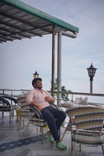 a man sitting in a chair on a patio at Sangam by Stotrak, Jhula Ghar Mussoorie in Mussoorie