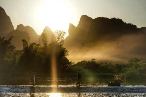 two people standing in the water in front of a river at The Apsara Lodge-Airport or TS Free pick-up over 3 nights in Yangshuo